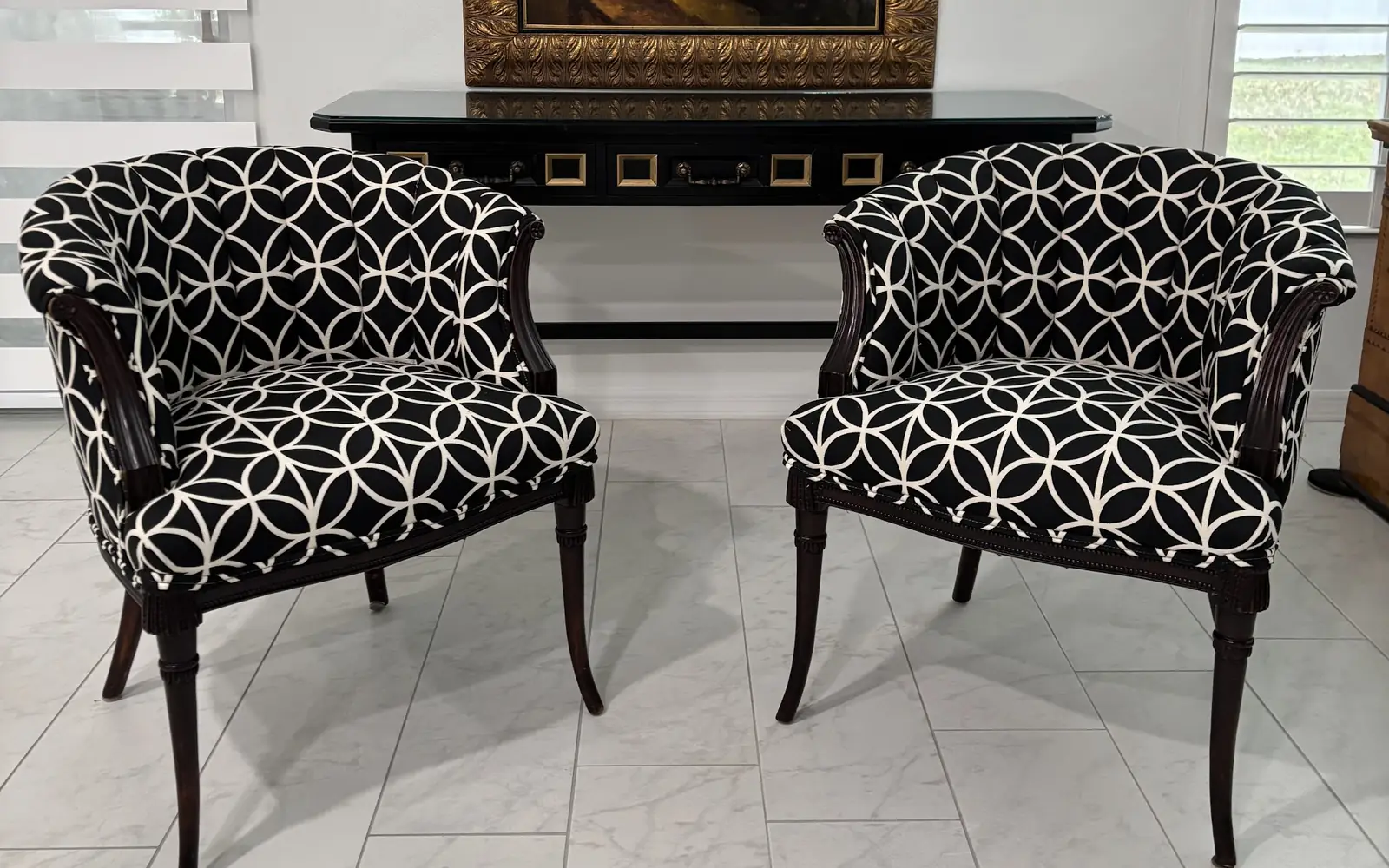 Two barrel chairs re-covered in a black and white lattice print on a white tile floor
